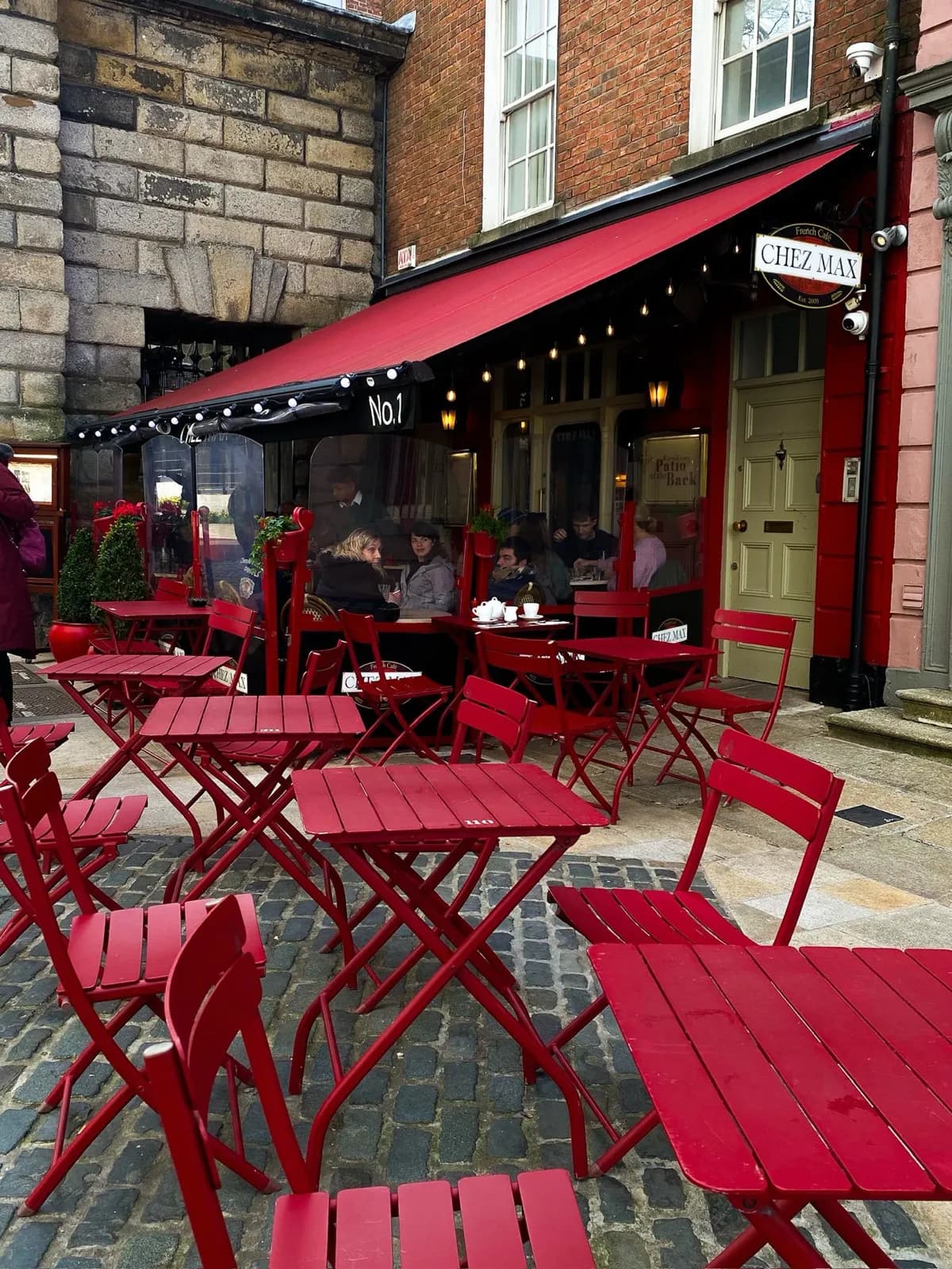 Red bistro tables and chairs on the terrace of Chez Max, beside the gates of Dublin Castle