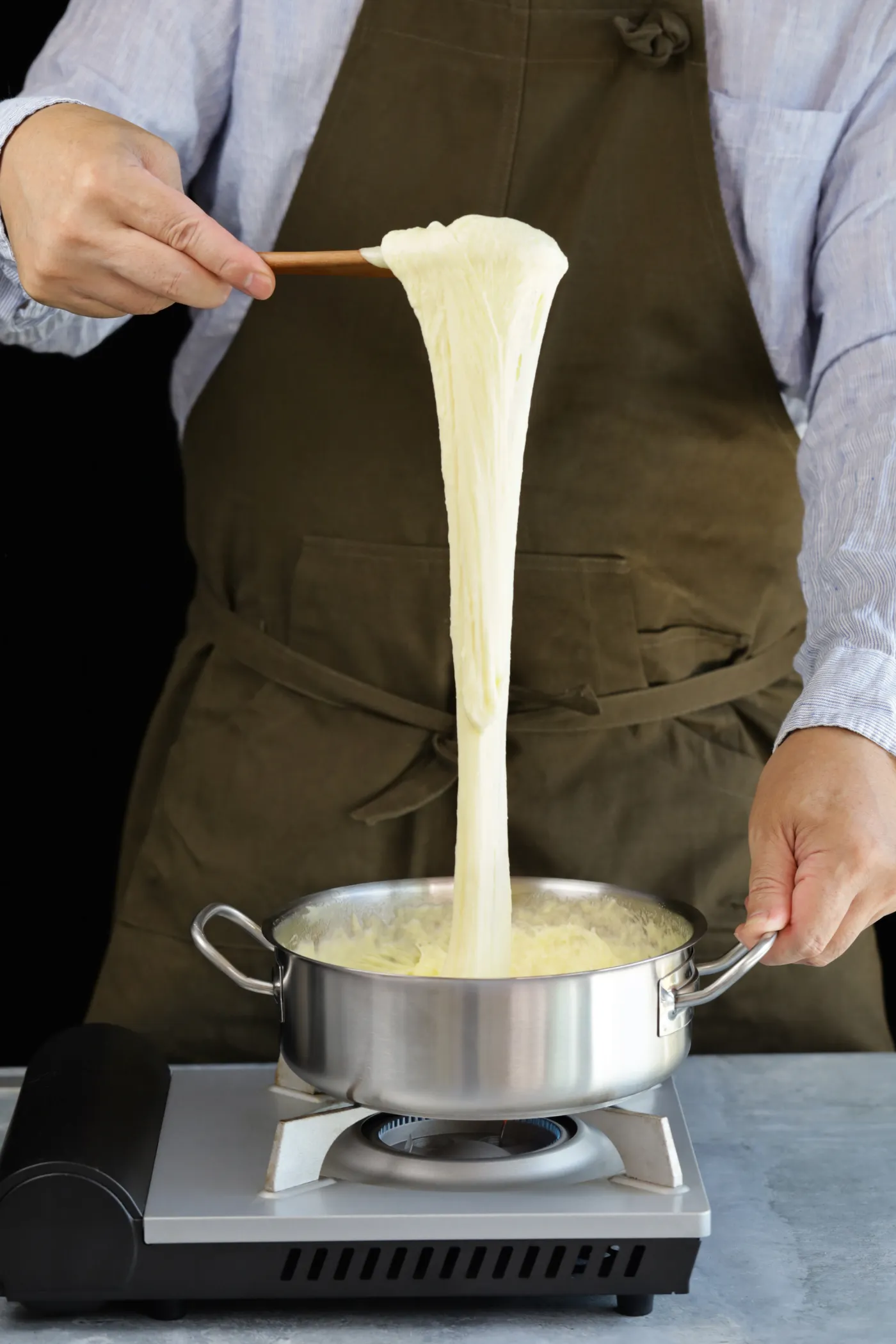 Stretching a spoonful of aligot from a pot