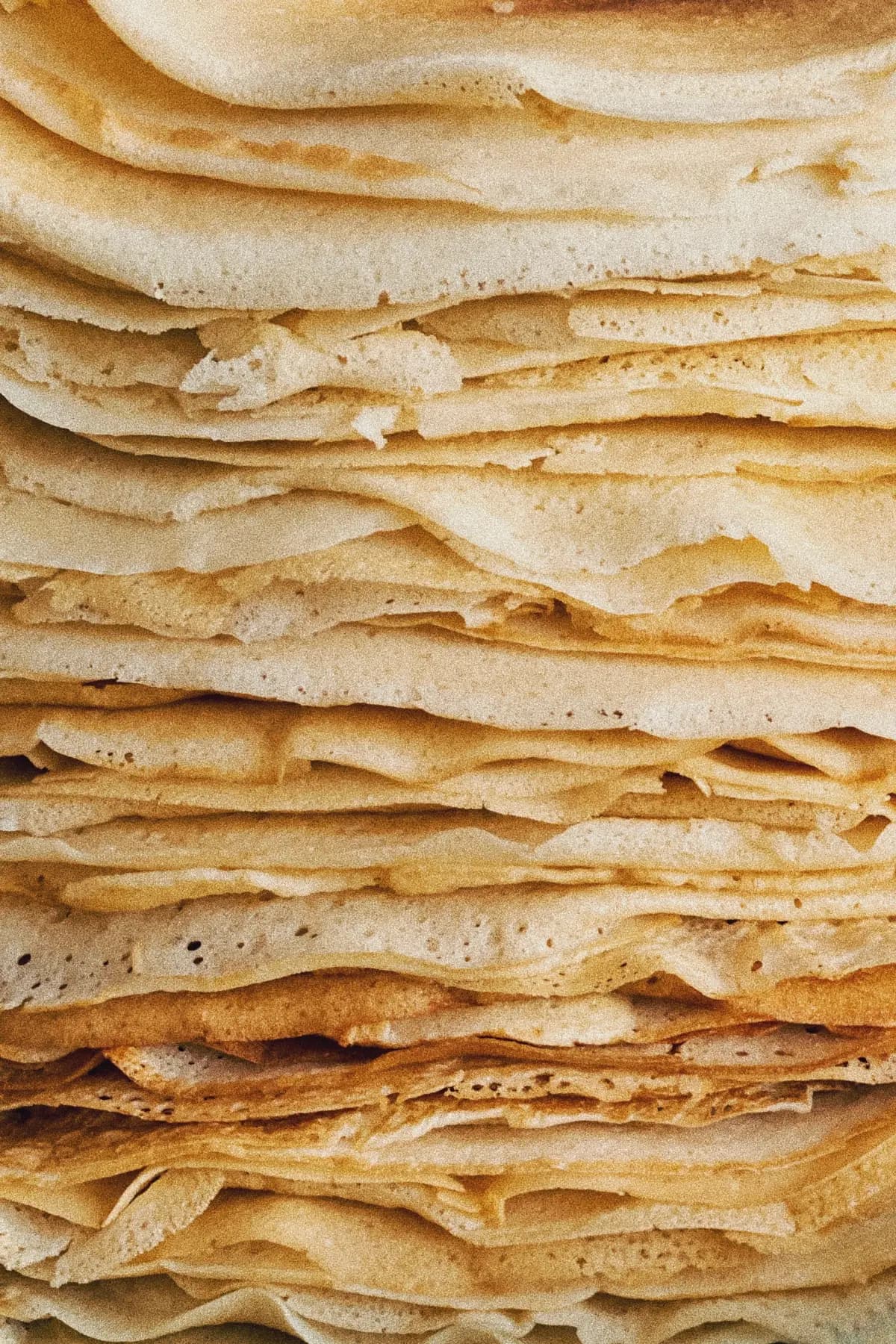 A tall stack of thin golden crêpes