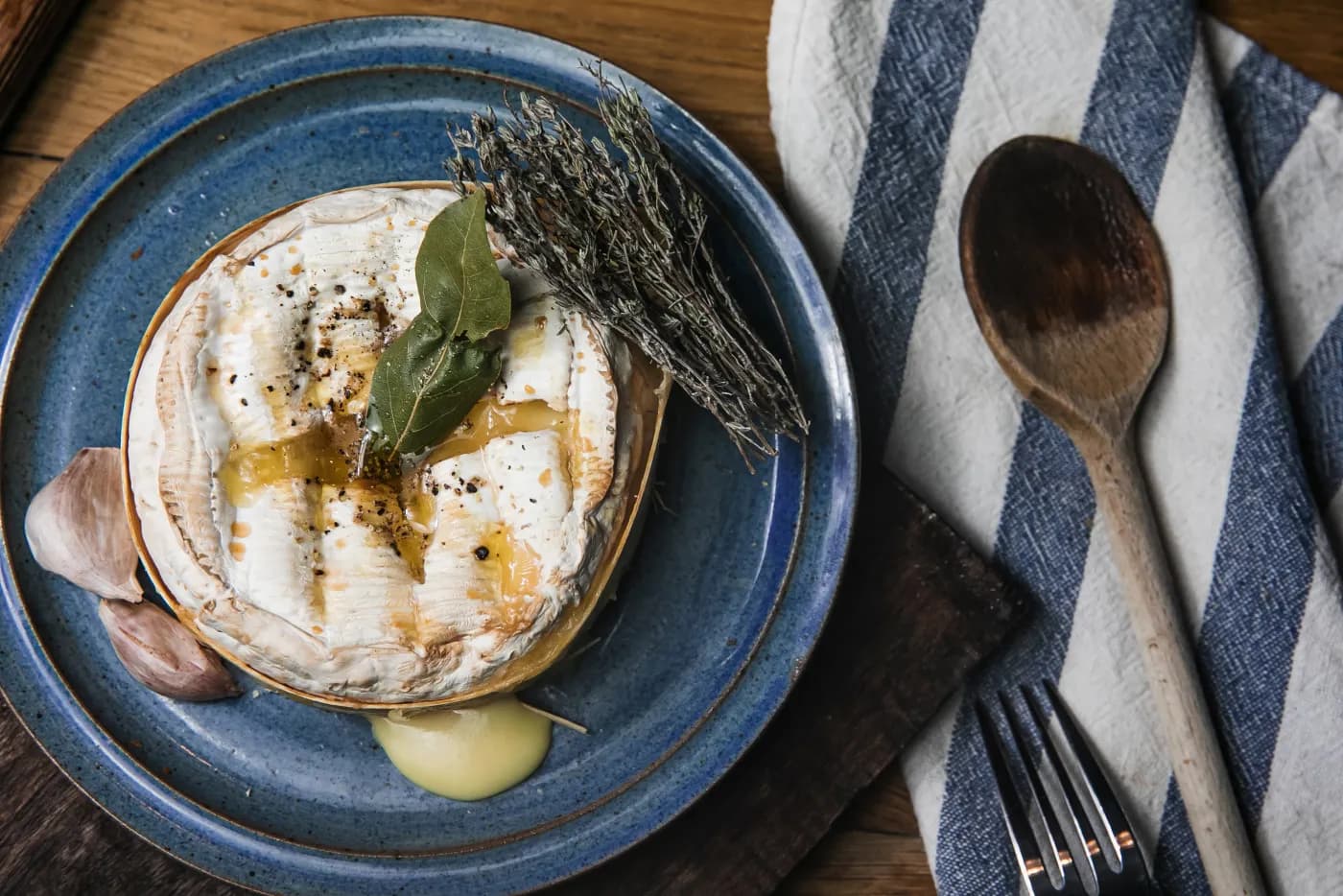 Baked Mont d’Or cheese with herbs on a blue plate