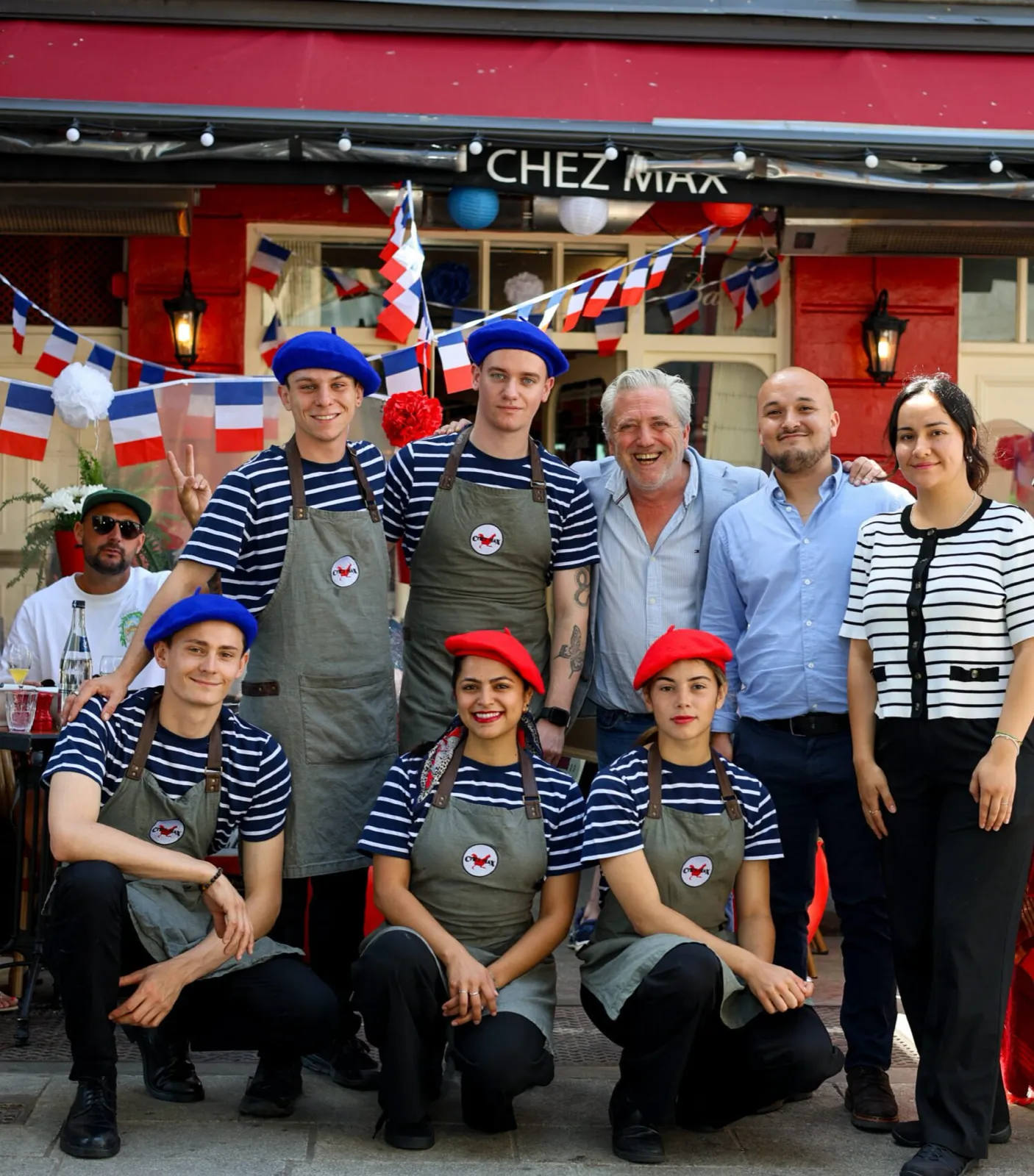 The international Chez Max team in berets and breton stripes with Max, outside the restaurant