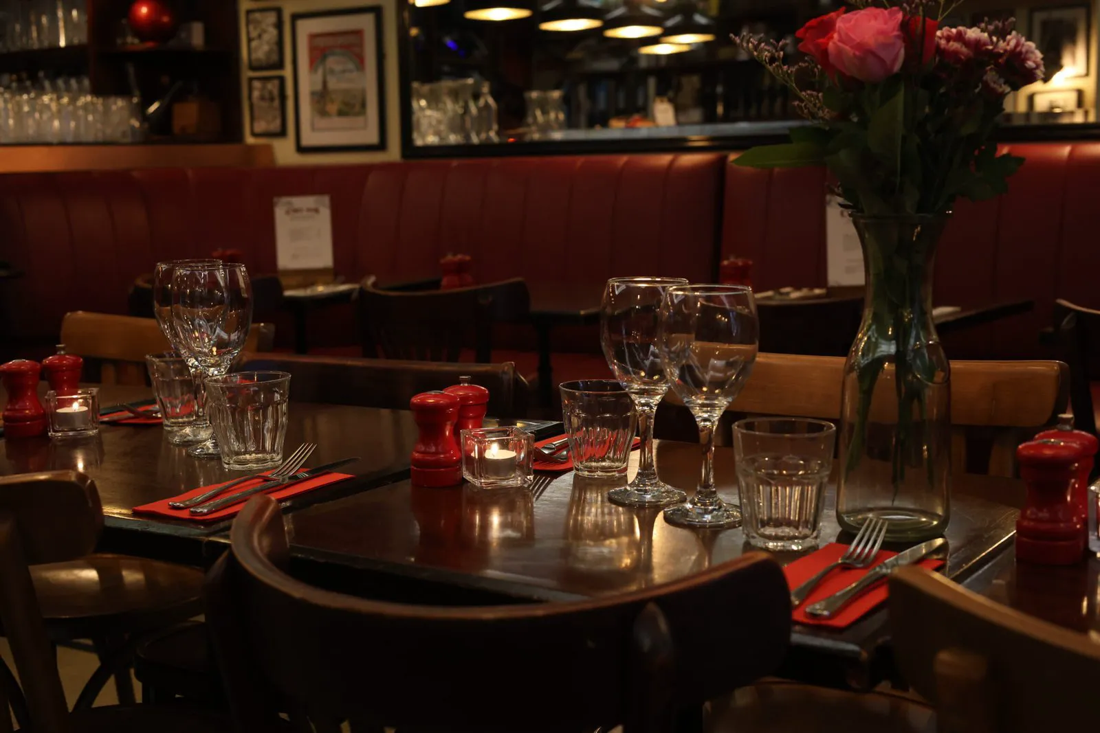 Candlelit tables set for dinner at Chez Max, red pepper mills and fresh roses